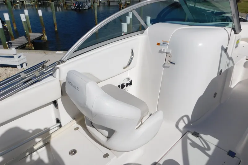 Slide: The Image of 2014 Robalo R207 Dual Console boat interior with white seating and dock view. - 14