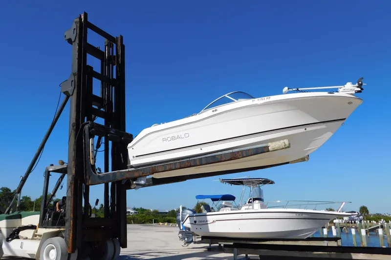 Slide: The Image of 2014 Robalo R207 Dual Console boat lifted by forklift under clear blue sky. - 2