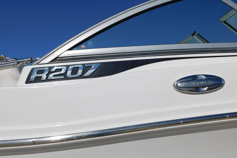 Slide: The Image of 2014 Robalo R207 Dual Console boat, sleek design with chrome detailing against blue sky. - 5