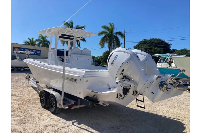 Slide: The Image of 2026 Bluewater 25 T boat with Yamaha engines on a trailer, sunny day, palm trees. - 3