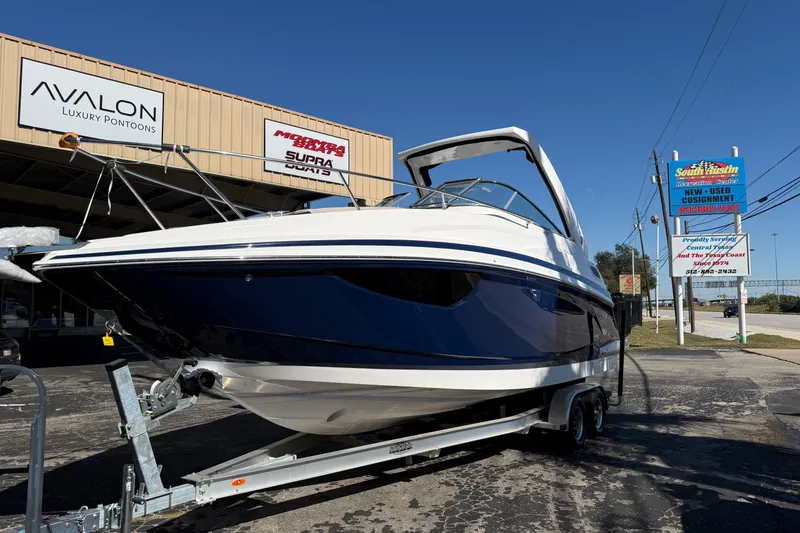 Slide: The Image of 2026 Regal 28 Express boat on trailer outside dealership, showcasing sleek design. - 2