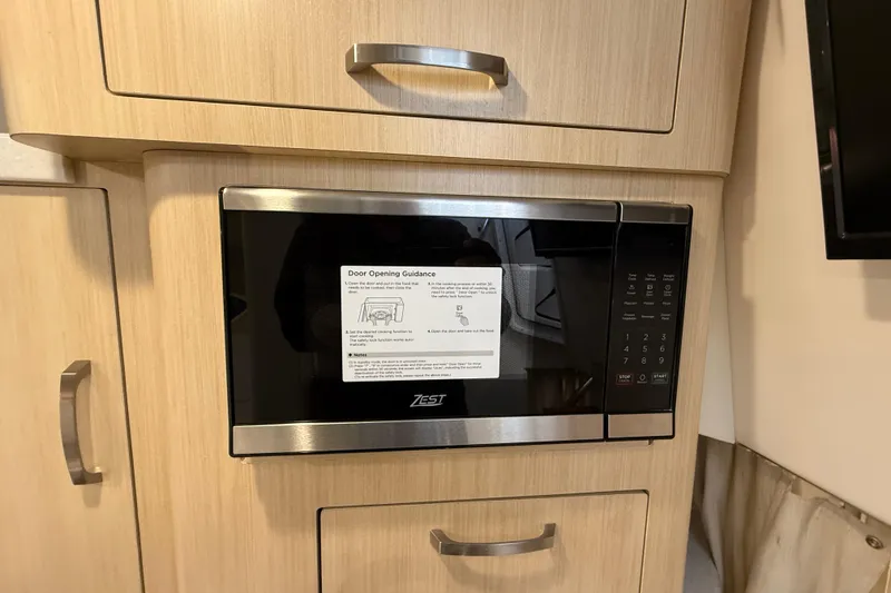 Slide: The Image of Microwave in 2026 Regal 28 Express boat kitchen, with wooden cabinetry and modern design. - 44