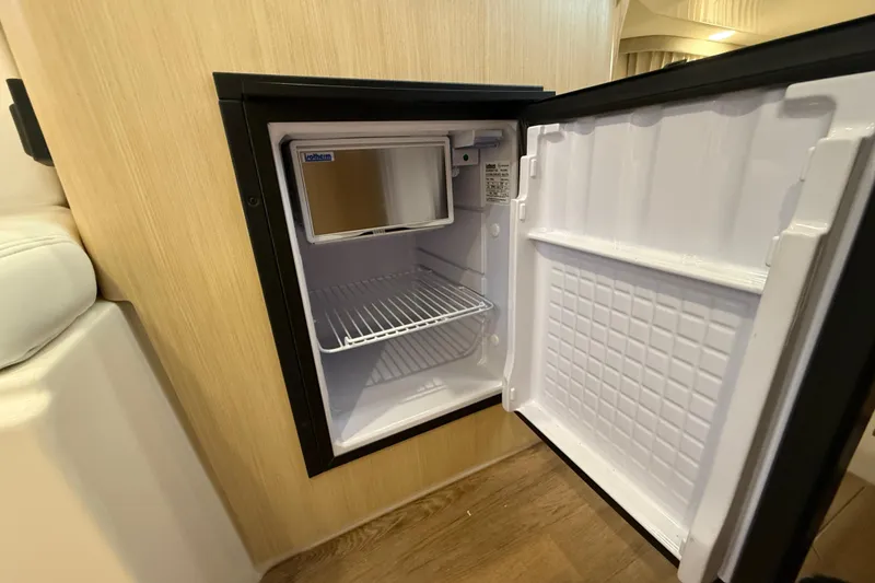 Slide: The Image of Open mini fridge inside 2026 Regal 28 Express boat, showcasing compact storage space. - 49