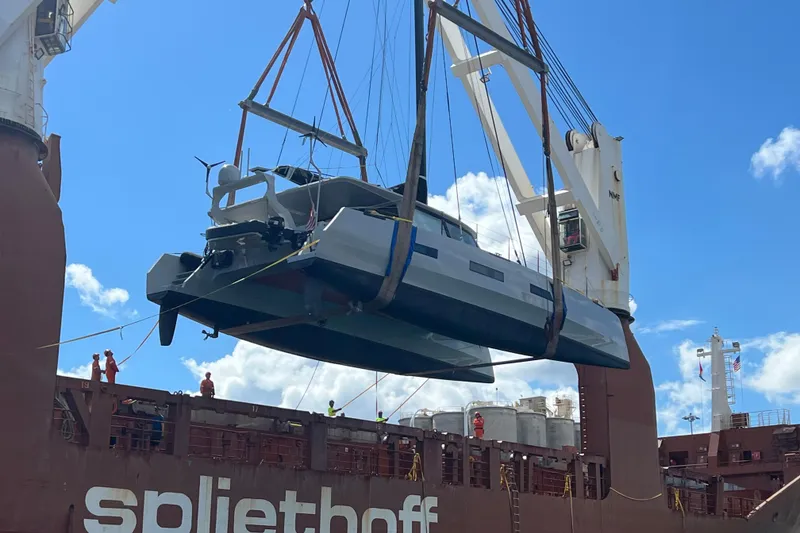 Slide: The Image of 2017 Harvey Yachts 58 being lifted onto a cargo ship under a clear blue sky. - 115