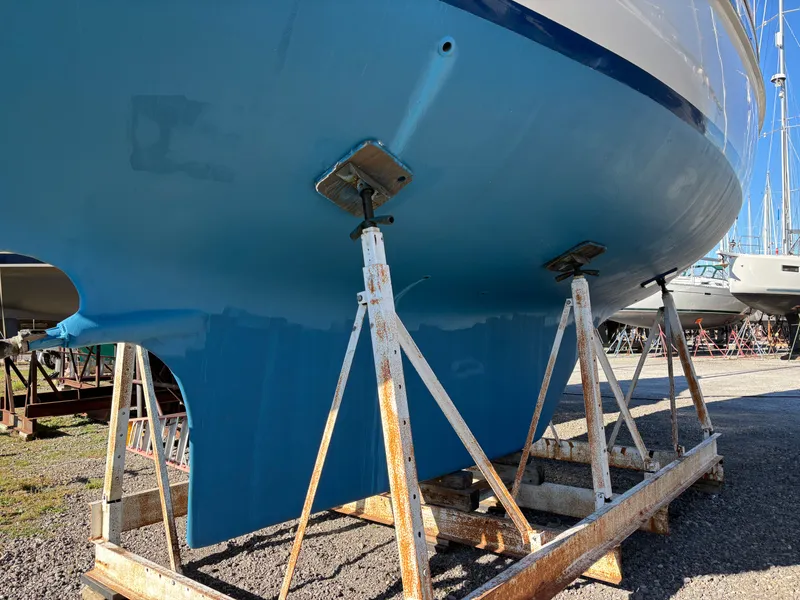 Slide: The Image of 1979 Hallberg-Rassy 38 sailboat on stands, blue hull, in a boatyard. - 12