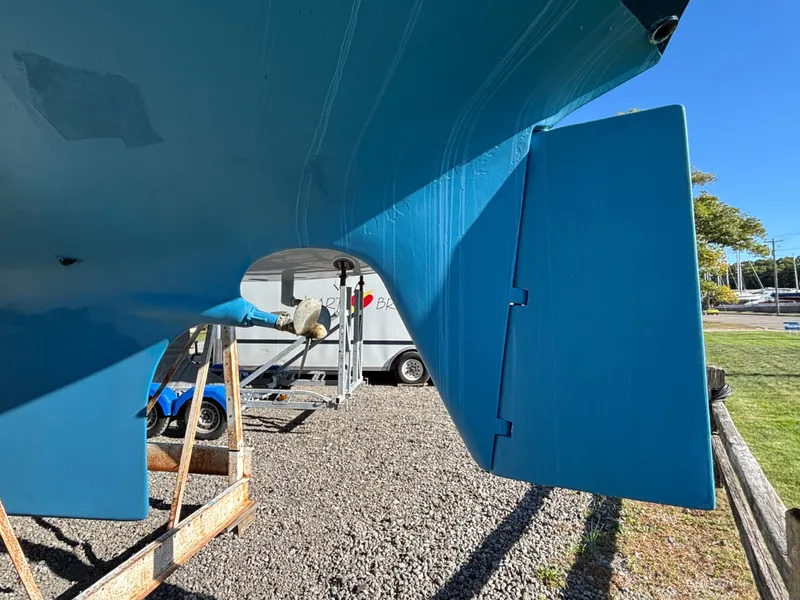 Slide: The Image of 1979 Hallberg-Rassy 38 sailboat rudder and hull, displayed on a gravel surface. - 13
