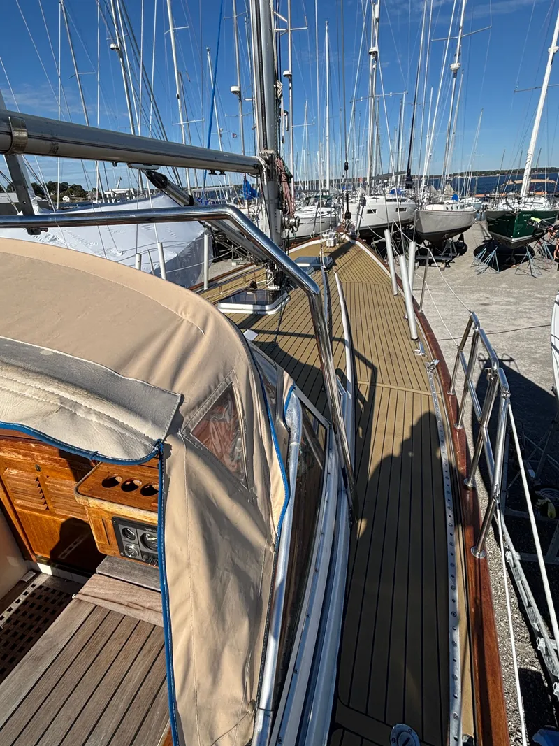 Slide: The Image of 1979 Hallberg-Rassy 38 sailboat docked, showcasing teak deck and cockpit cover. - 24