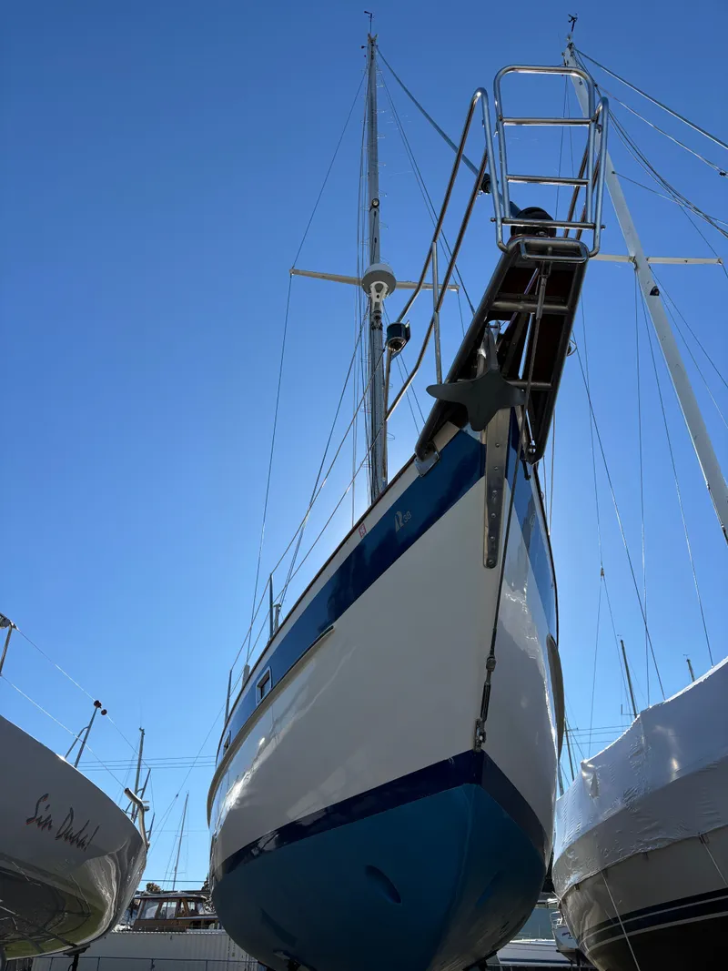 Slide: The Image of 1979 Hallberg-Rassy 38 sailboat on land, viewed from below against a clear blue sky. - 4
