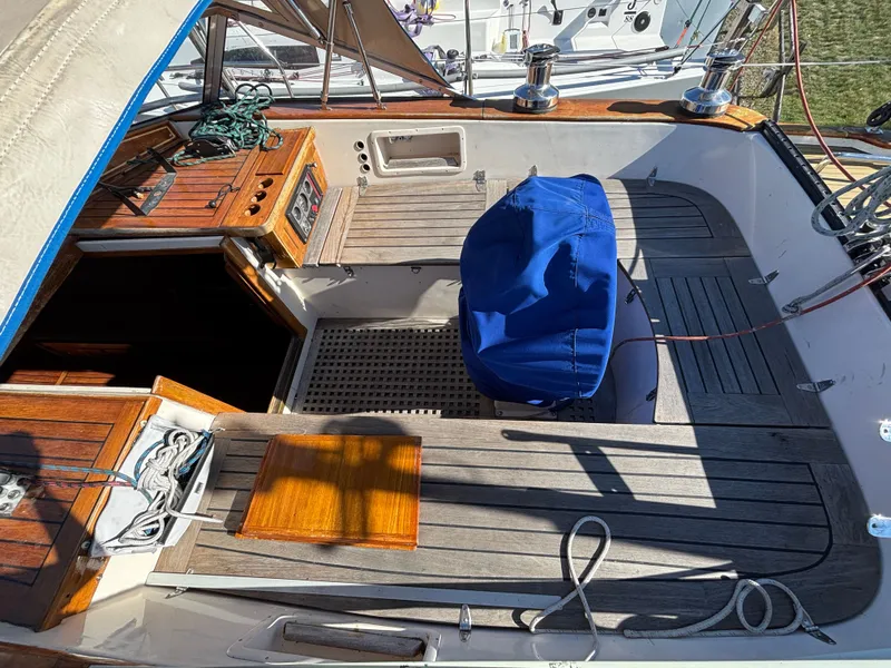 Slide: The Image of 1979 Hallberg-Rassy 38 sailboat cockpit with wooden deck and blue-covered wheel. - 44