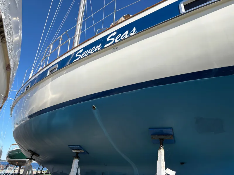 Slide: The Image of 1979 Hallberg-Rassy 38 sailboat "Seven Seas" on stands, blue hull, clear sky background. - 6