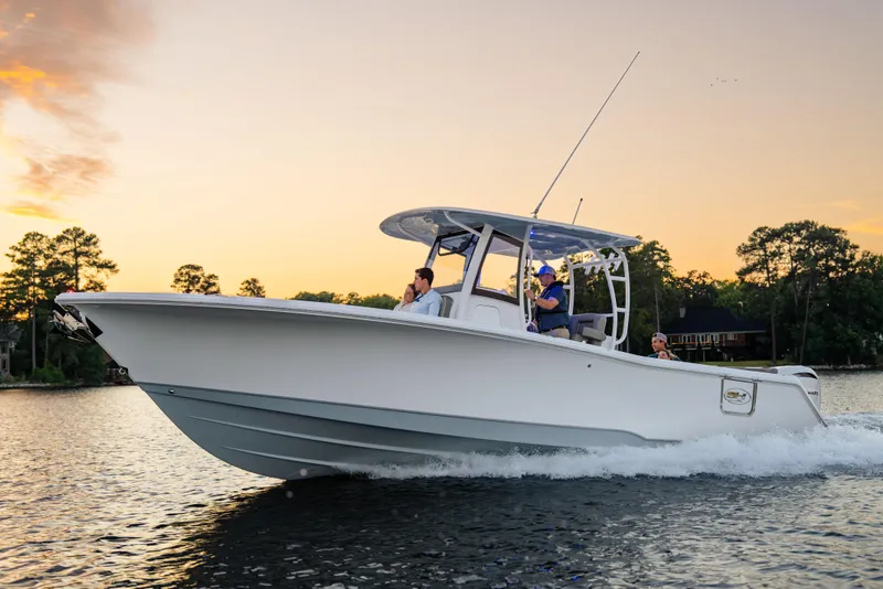 Slide: The Image of 2026 Sea Hunt Ultra 305 Coffin Box boat cruising on a serene lake at sunset. - 12