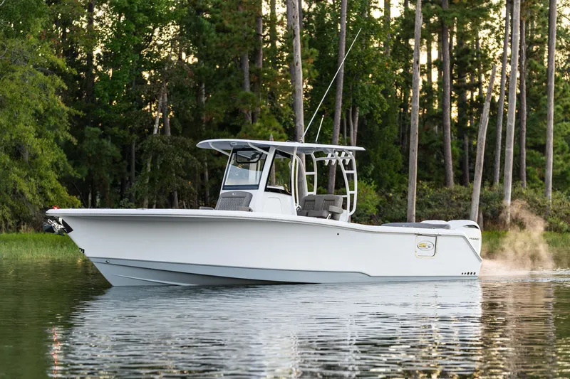 Slide: The Image of 2026 Sea Hunt Ultra 305 Coffin Box boat on calm water, surrounded by trees. - 13