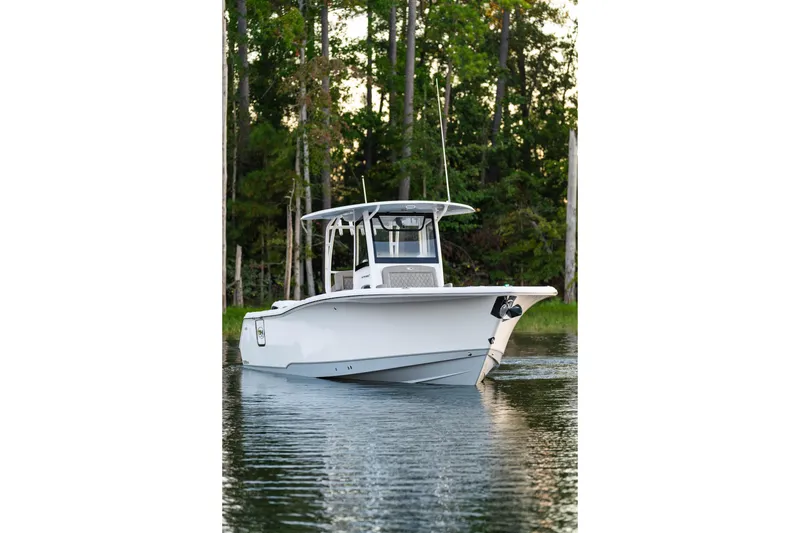 Slide: The Image of 2026 Sea Hunt Ultra 305 Coffin Box boat on calm water, surrounded by trees. - 32