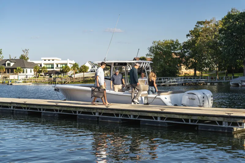 Slide: The Image of People boarding a 2026 Sea Hunt Ultra 305 Coffin Box boat at a sunny dock. - 6