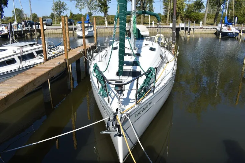 Slide: The Image of 1996 Beneteau Oceanis 321 sailboat docked in a marina, surrounded by calm water. - 1