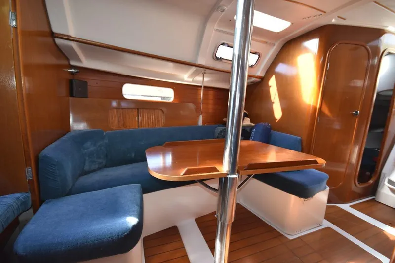 Slide: The Image of Interior of 1996 Beneteau Oceanis 321 sailboat with wooden table and blue seating. - 28