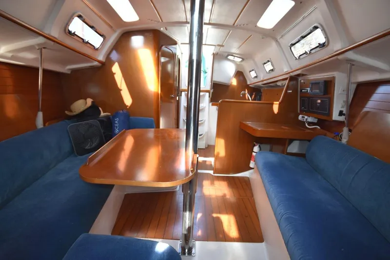 Slide: The Image of Interior of 1996 Beneteau Oceanis 321 sailboat with blue seating and wooden finishes. - 29