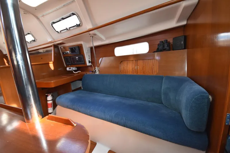 Slide: The Image of Interior of 1996 Beneteau Oceanis 321 sailboat with blue sofa and wooden accents. - 30