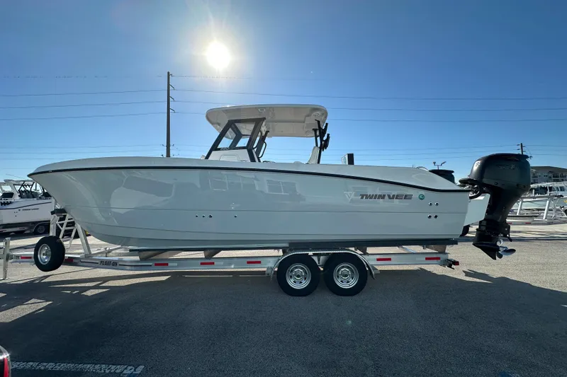 Slide: The Image of 2026 Twin Vee 280 GFX2 CC boat on trailer under bright sun. - 3