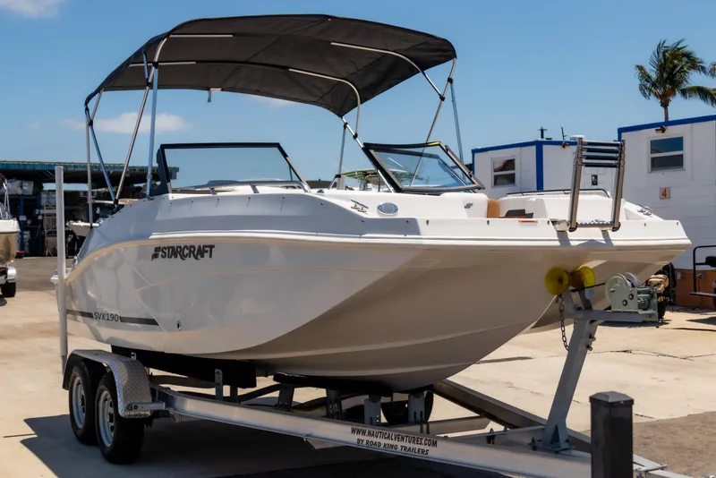 Slide: The Image of 2023 Starcraft SVX 190 OB boat on trailer, with canopy, parked outdoors. - 3