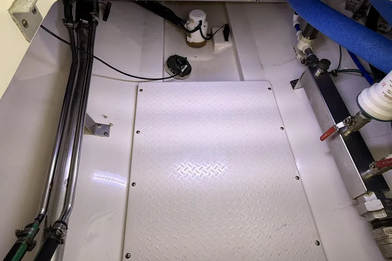 Slide: The Image of Engine compartment of a 2012 Everglades 350LX boat, featuring pipes and mechanical components. - 84