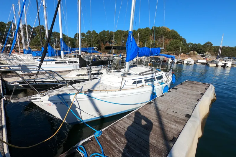 The Image of 1986 Catalina 27 sailboat docked at marina with blue covers and clear sky. - 0