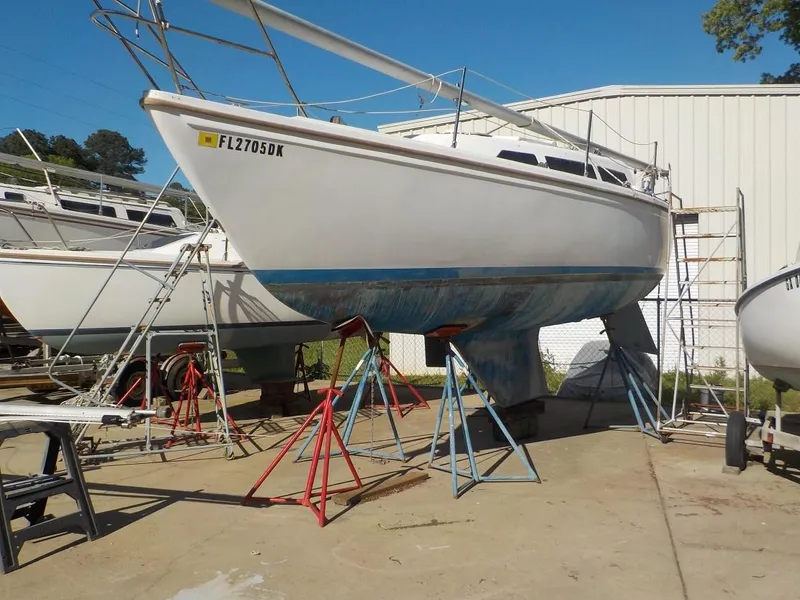 Slide: The Image of 1986 Catalina 27 sailboat on stands, white hull, blue bottom, outdoors near a building. - 16