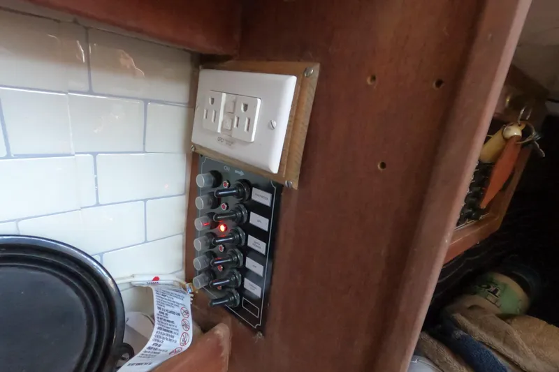 Slide: The Image of Electrical panel and outlet in 1986 Catalina 27 boat interior, featuring wood and tile accents. - 8