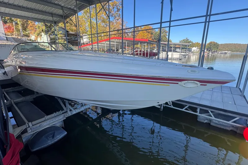 Slide: The Image of 2005 Baja 342 speedboat docked in a marina, featuring sleek white design with red and yellow stripes. - 2