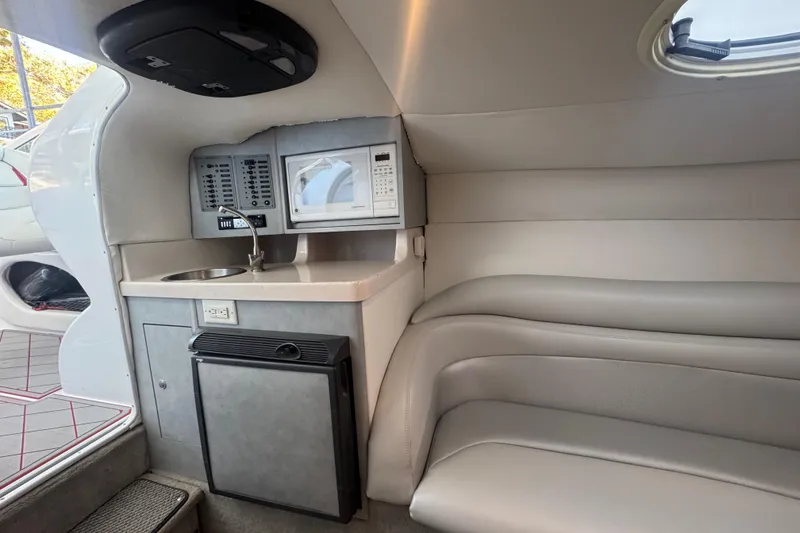 Slide: The Image of Interior of a 2005 Baja 342 boat featuring a kitchenette with sink, microwave, and seating. - 21