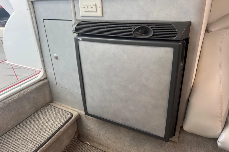 Slide: The Image of Compact refrigerator in 2005 Baja 342 boat interior, featuring gray paneling and carpeted flooring. - 25