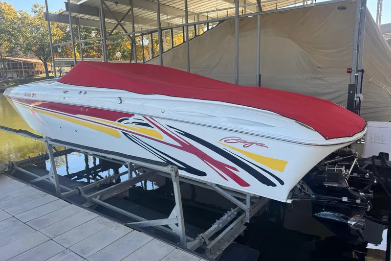 Slide: The Image of 2005 Baja 342 speedboat with red cover on lift, vibrant graphics, docked in marina. - 36