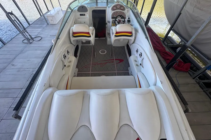 Slide: The Image of 2005 Baja 342 boat interior with white seating and dashboard, docked by the water. - 6