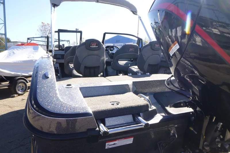 Slide: The Image of 2026 Ranger 2080MS boat interior with seating and motor, parked outdoors. - 10