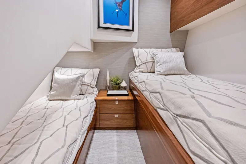 Slide: The Image of 2025 Viking 64 Convertible yacht cabin with twin beds, modern decor, and framed artwork. - 33