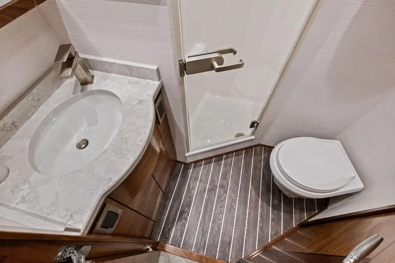 Slide: The Image of 2025 Viking 64 Convertible yacht bathroom with modern sink, shower, and toilet. - 35