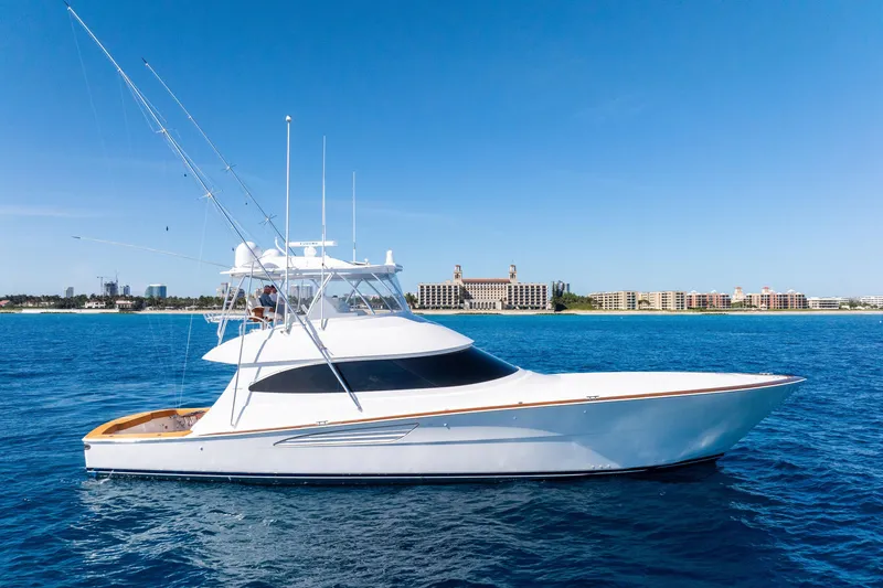 Slide: The Image of 2025 Viking 64 Convertible yacht cruising on blue ocean near coastal cityscape. - 4