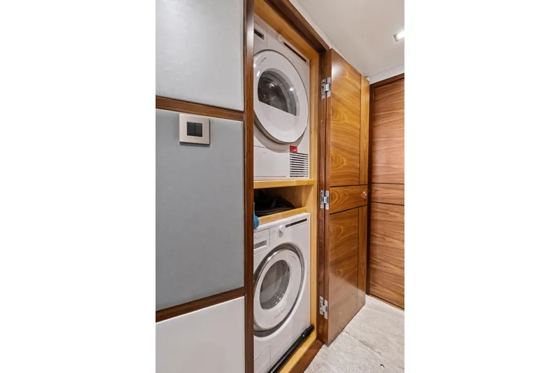 Slide: The Image of Laundry area in 2025 Viking 64 Convertible yacht with stacked washer and dryer. - 42