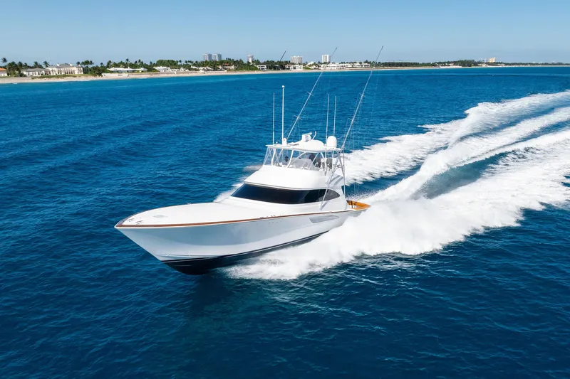 Slide: The Image of 2025 Viking 64 Convertible yacht cruising on open blue ocean near coastline. - 6