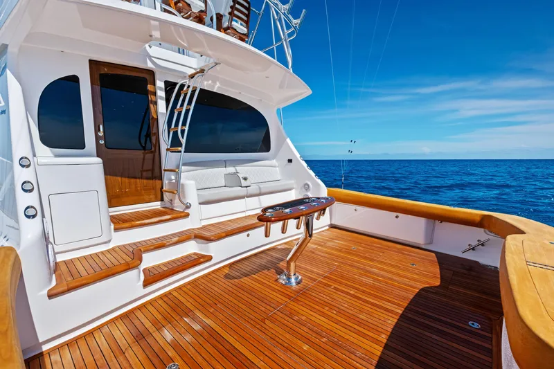 Slide: The Image of 2025 Viking 64 Convertible yacht deck with wooden flooring, ocean view, and seating area. - 61