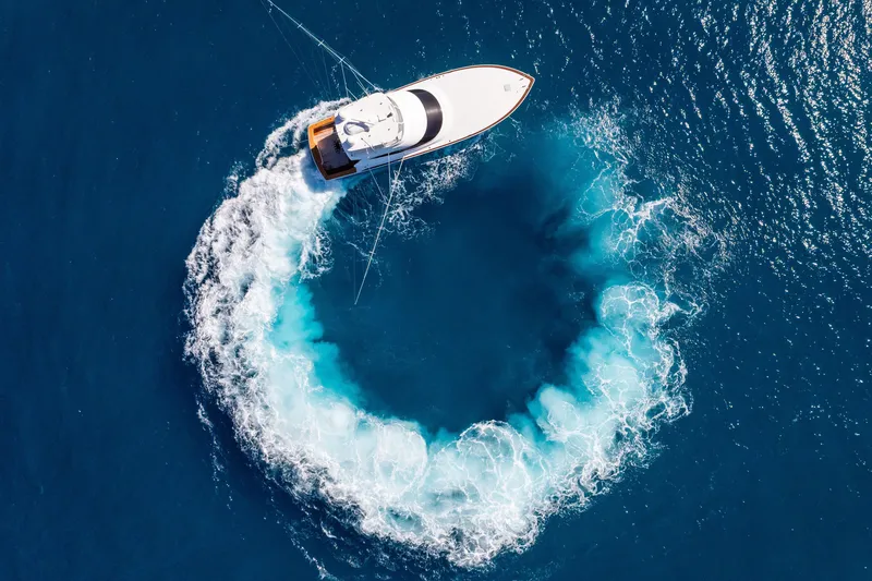 Slide: The Image of Aerial view of 2025 Viking 64 Convertible yacht creating a circular wake in blue ocean. - 63